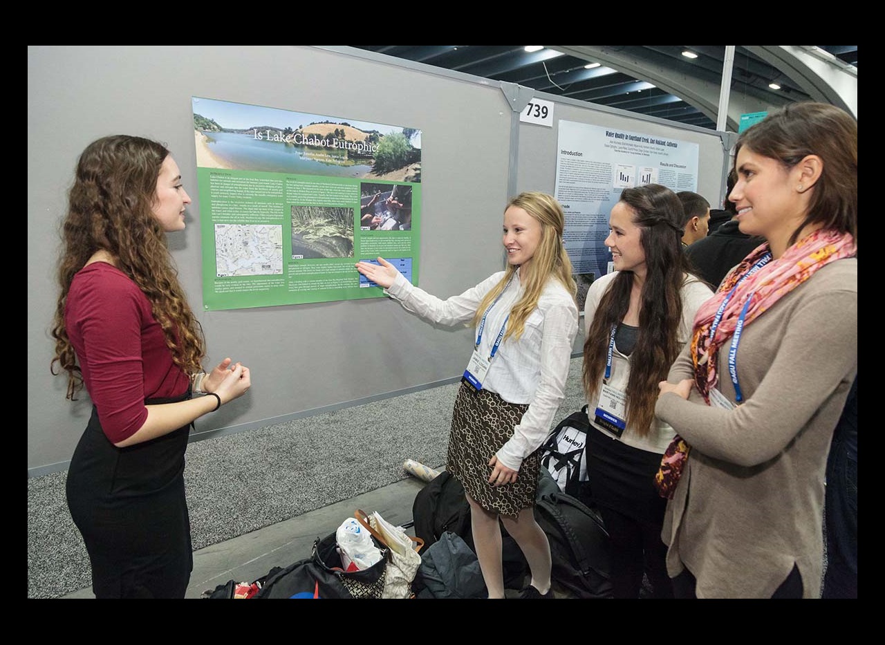 Female students discussing a poster OUTSTANDING STUDENT PRESENTATION AWARDS (OSPA