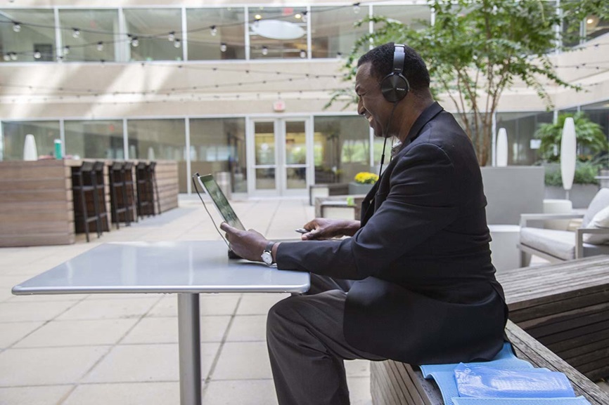 Man with headphones, holding ipad, sitting at table in office glacier