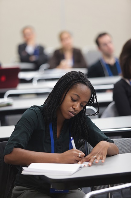 Young Female writing in notebook in classroom Diversity and inclusion
