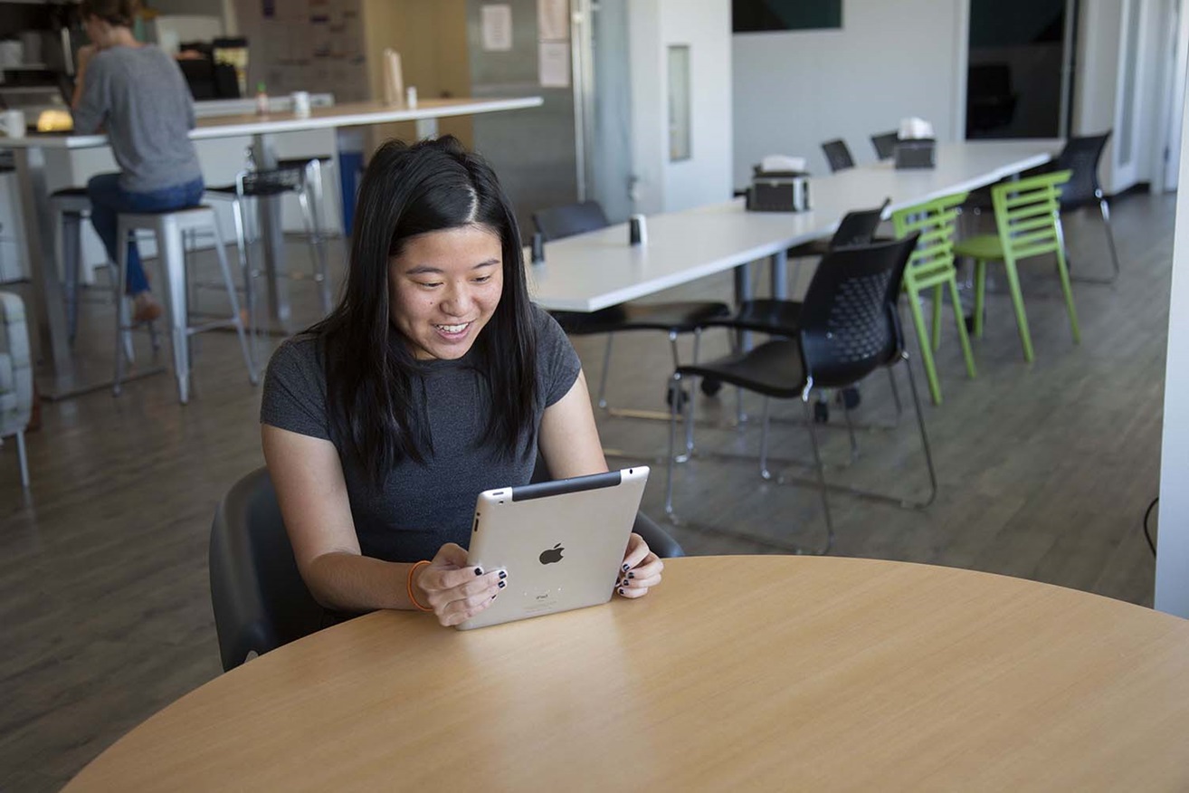 Woman smiling while holding ipad in office Woman smiling while holding ipad in office