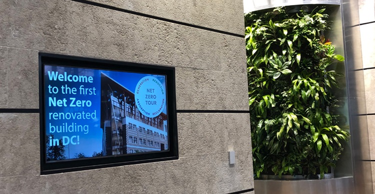 Net zero building sign near green wall.